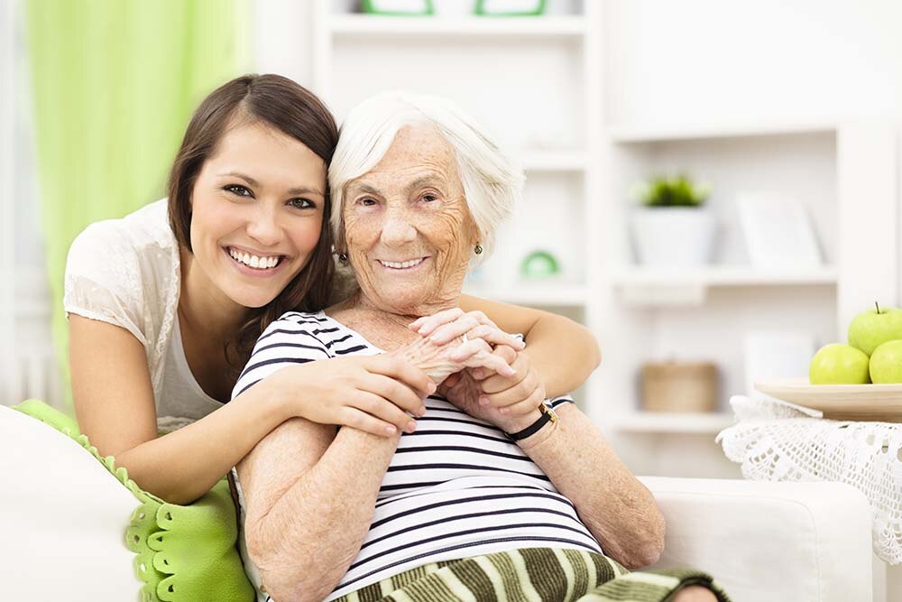 Elderly and young woman hugging and smiling together.