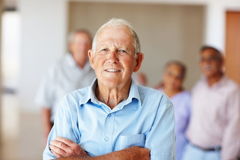 Elderly man standing in front of a group of elderly people.