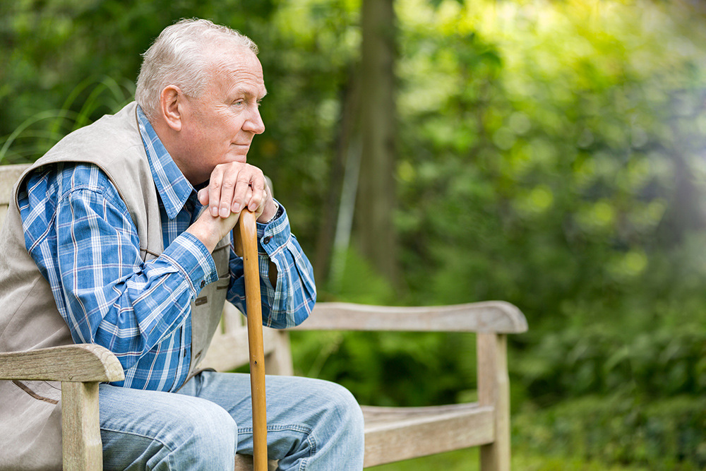 Elderly man sitting outside on a bench.