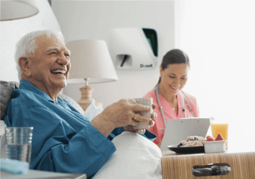 Elderly man using Dosell medication dispensing robot.